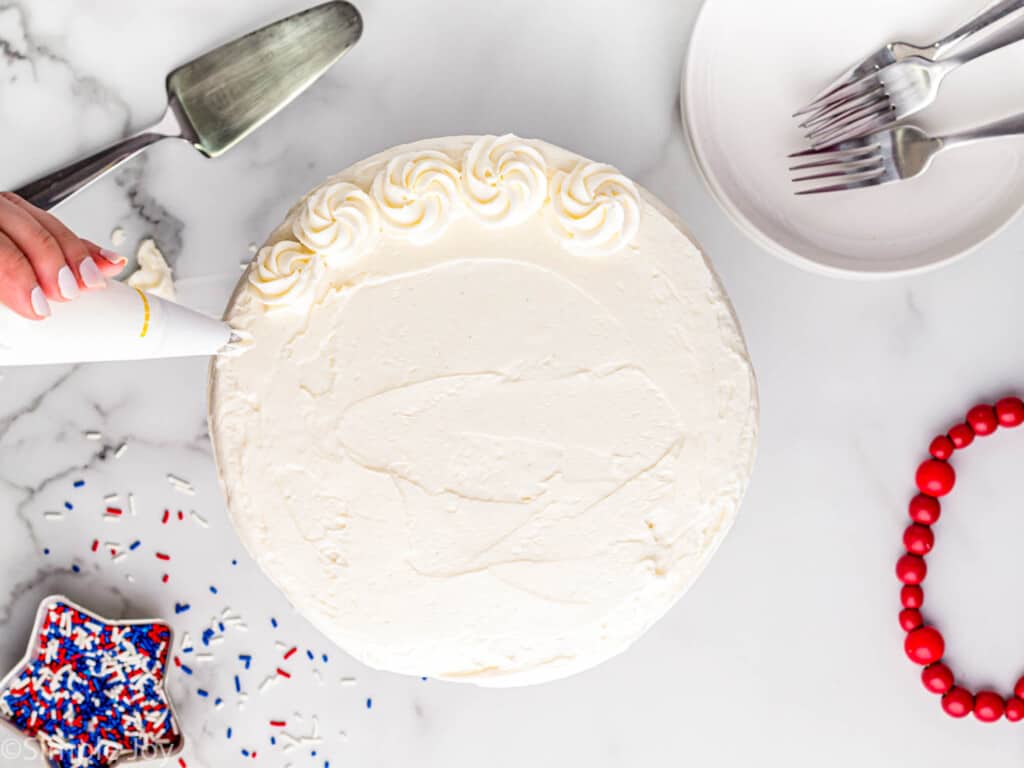 overhead of a white layer cake being frosted