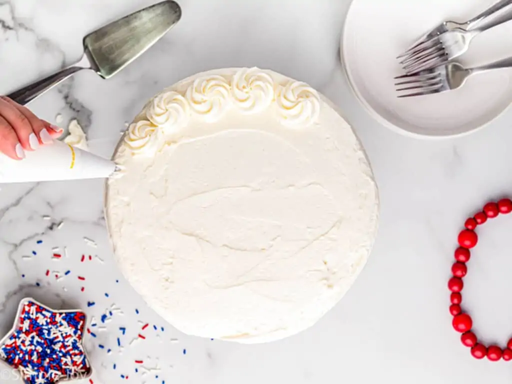 overhead of a white layer cake being frosted