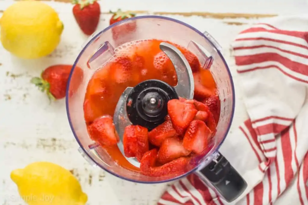 overhead view of a food processor with strawberries (that were frozen and now thawed) and liquid