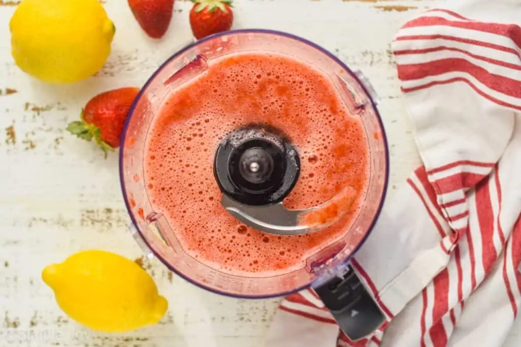 overhead view of food processor after strawberries and lemon juice have been pureed; liquid is frothy