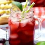 a glass of cherry limeade garnished with a lime wedge