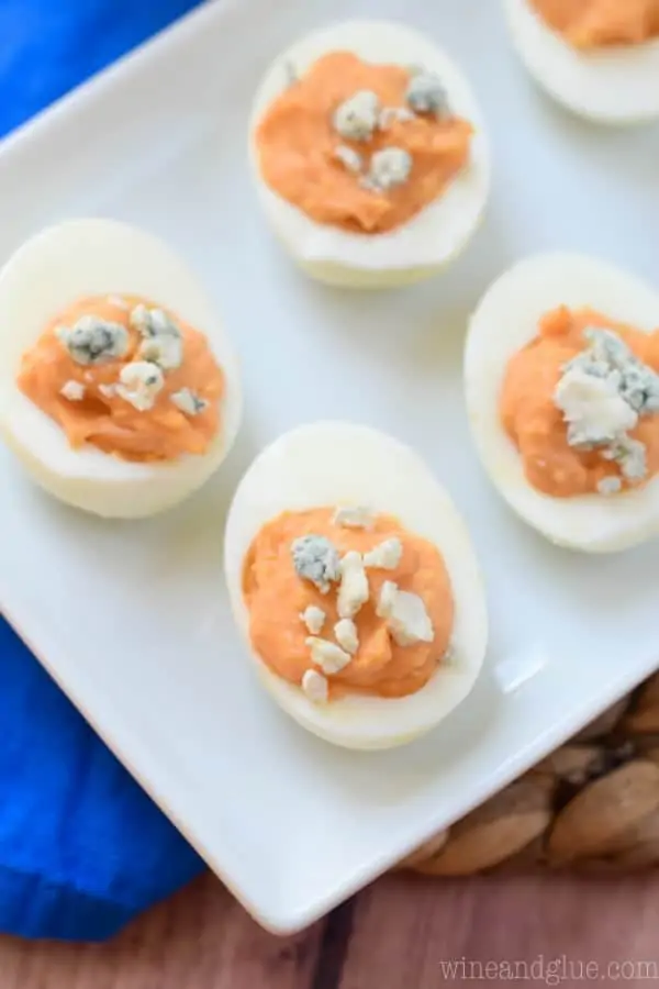 An overhead photo of the Buffalo Deviled Eggs has a Buffalo Sauce color middle and topped with blue cheese crumble