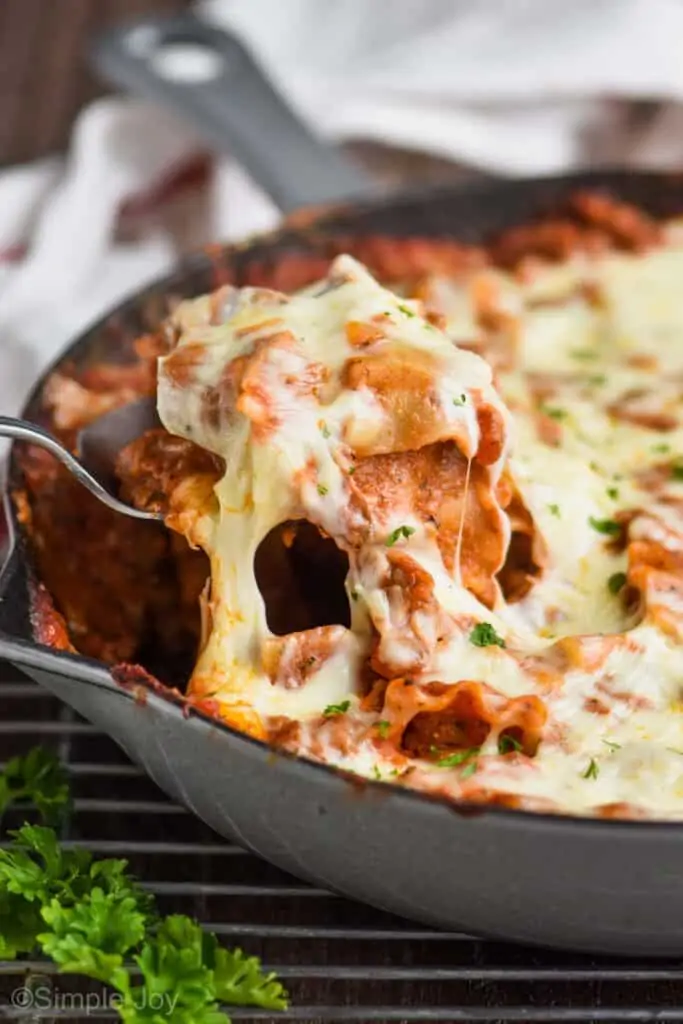 side view of a skillet and a spoon dishing up cheesy skillet lasagna