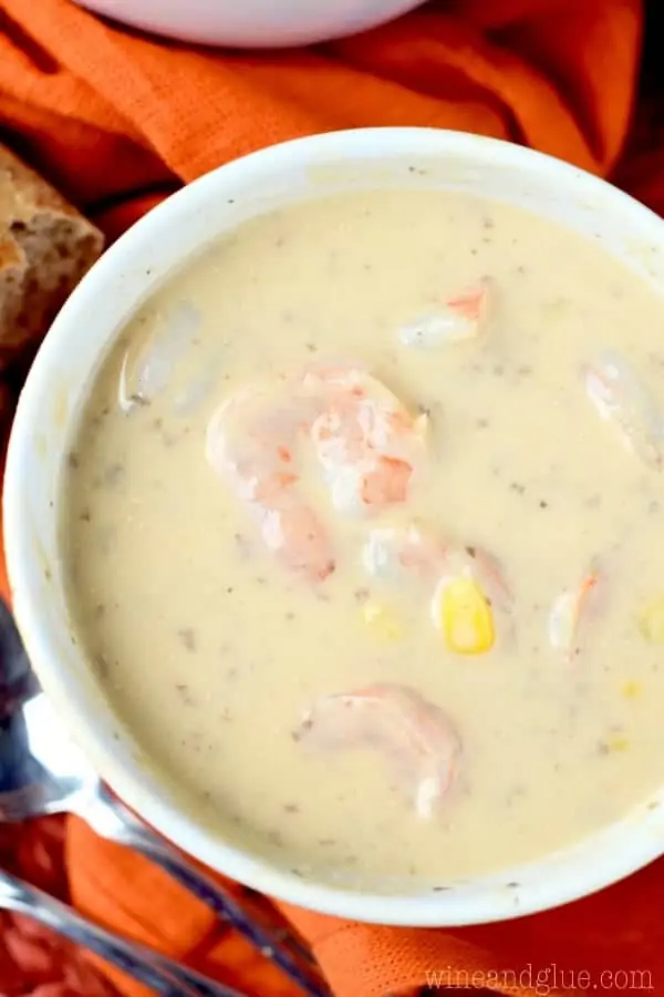 An overhead photo of the Spicy Shrimp Corn and Potato Bisque which has a yellow cream color with specks of pink and yellow form the shirmp and corn. 