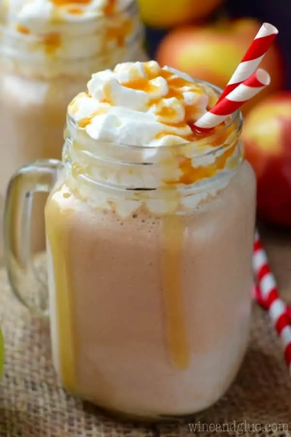 In two glass mason jars, the Caramel Apple Milkshakes are topped with whipped cream and dripping with caramel. 