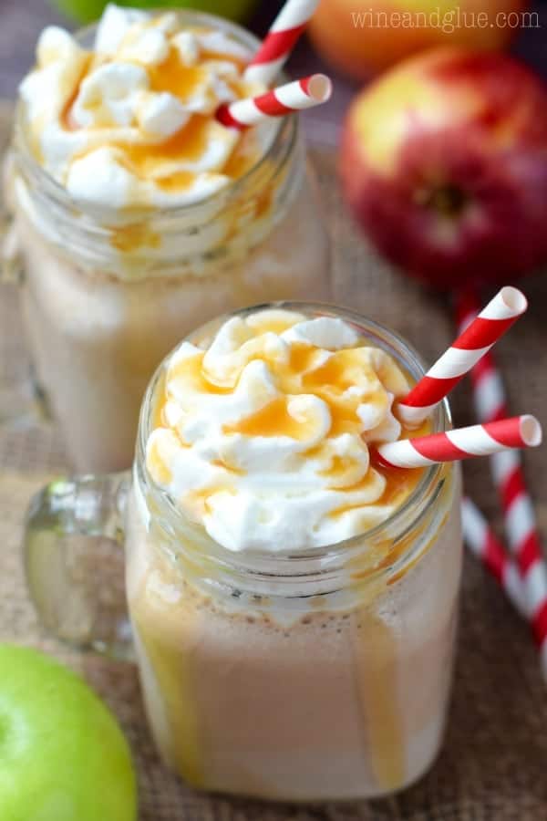 In two glass mason jars, the Caramel Apple Milkshakes are topped with whipped cream and dripping with caramel. 