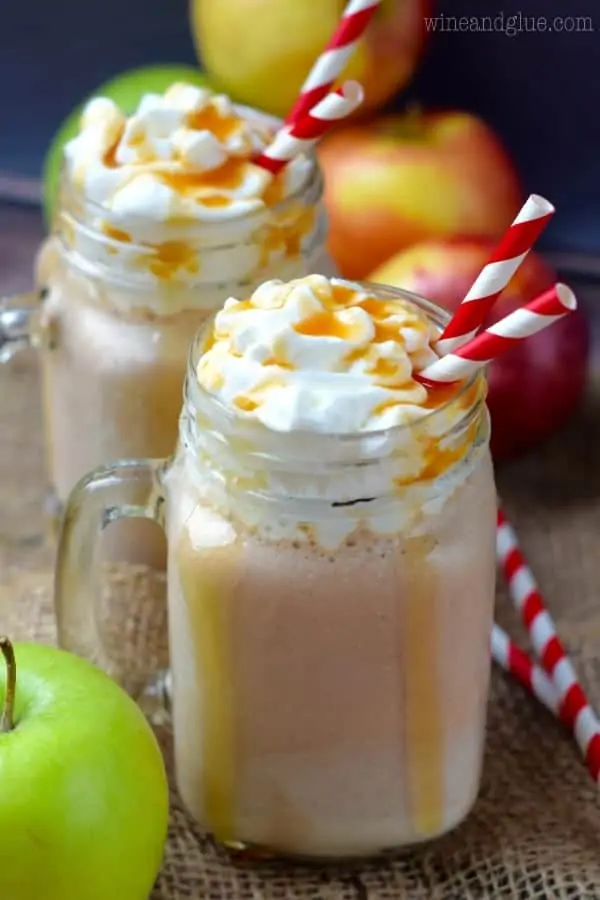 In two glass mason jars, the Caramel Apple Milkshakes are topped with whipped cream and dripping with caramel. 