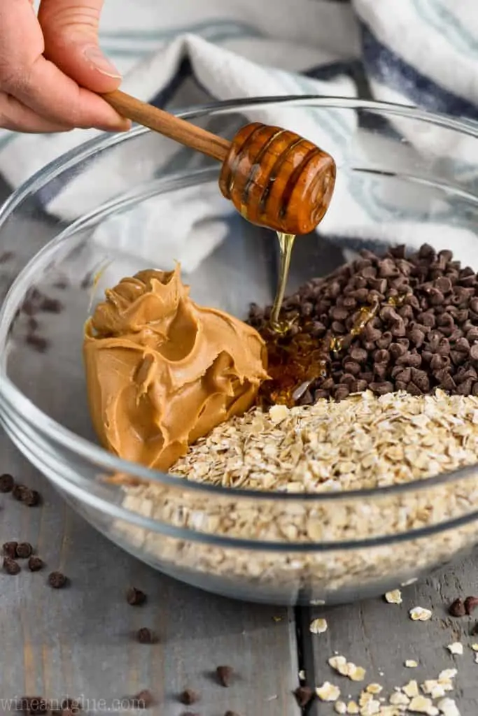 honey being poured into ingredients for oatmeal energy bites