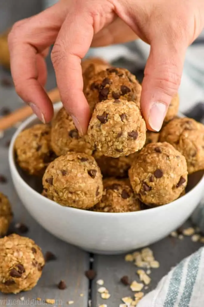 fingers setting down peanut butter energy balls into a bowl
