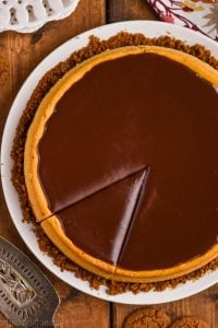overhead view of a pumpkin cheesecake covered in chocolate ganache with one piece cut into