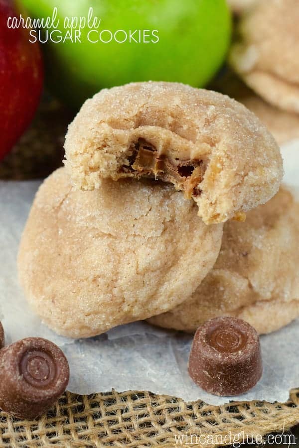 The Caramel Apple Sugar Cookies are piled on top of each other. The top most cookie has a bite showing the gooey caramel interior. 