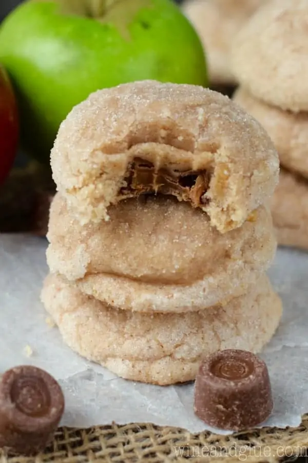 The Caramel Apple Sugar Cookies are stacked on top of each other. The top most cookie has a bite showing the gooey caramel interior. 