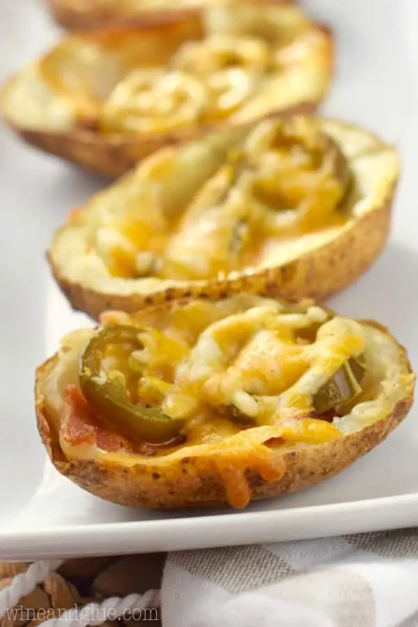 On a white plate, the Jalapeno Popper Potato Skin is lined up topped with melted cheese. 