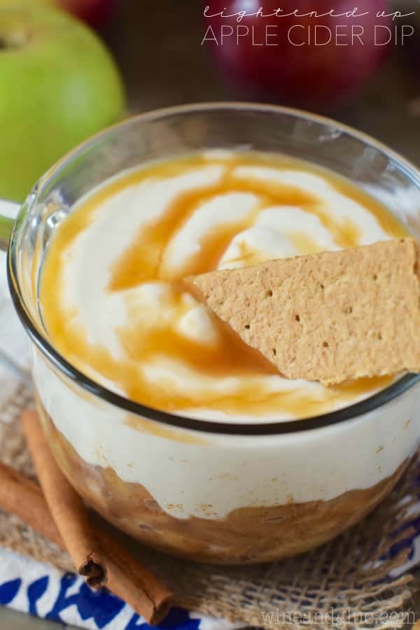 In a glass bowl, the Lightened Up Apple Cider Dip is topped with cream swirled with caramel. 