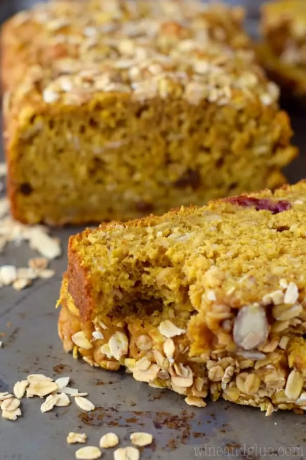 Slices of the Muesli Pumpkin Bread showing the pumpkin colored bread topped with oats, almonds, sunflower seeds, and more. 
