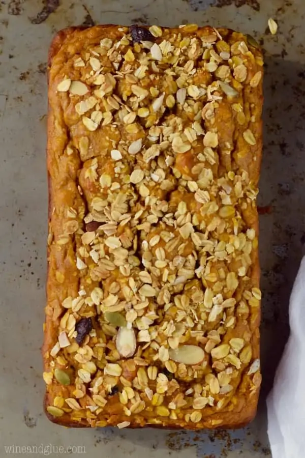 An overhead photo of the Muesli Pumpkin Bread showing the oats, sliced almonds, sunflower seeds, and more nuts sprinkled on top. 