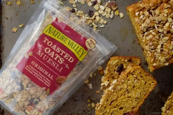 Slices of the Muesli Pumpkin Bread is next a package of the Nature Valley Toasted Oats Muesli. 