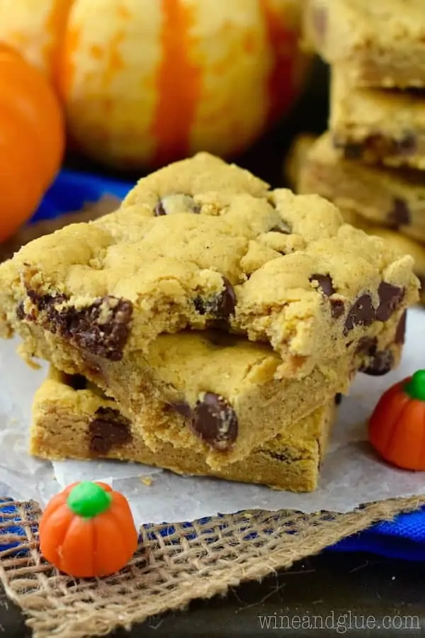 In a stack of three, the Pumpkin Brown Butter Cookie Bars have a light golden brown hue with chocolate chips oozing out. 