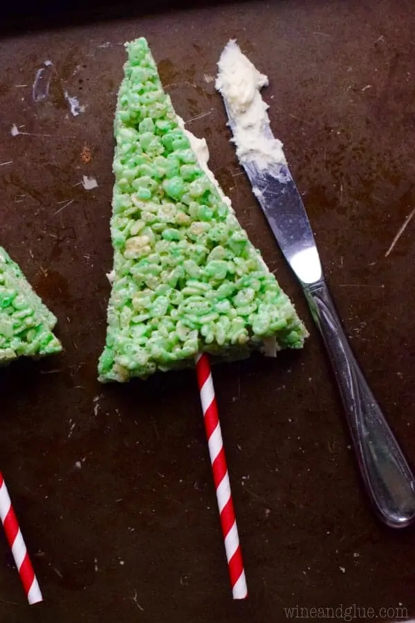 A triangular green Rice Krispie was placed on top of the swirled red straw and the other frosted Rice Krispie. 