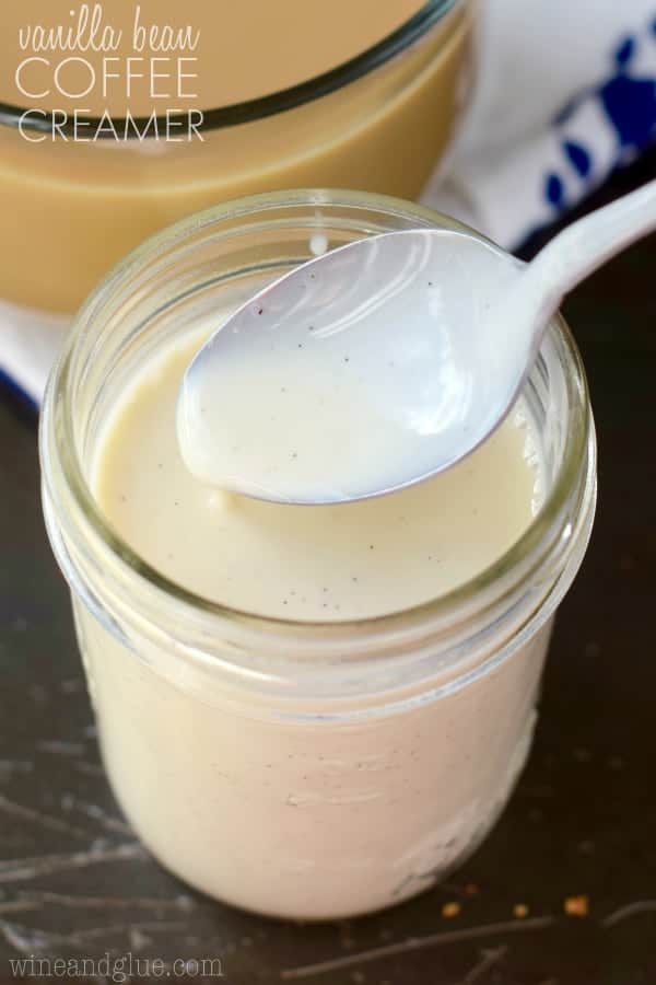 In a small mason jar, the Vanilla Bean Coffee Creamer has a pale white color with black dots with vanilla bean. 