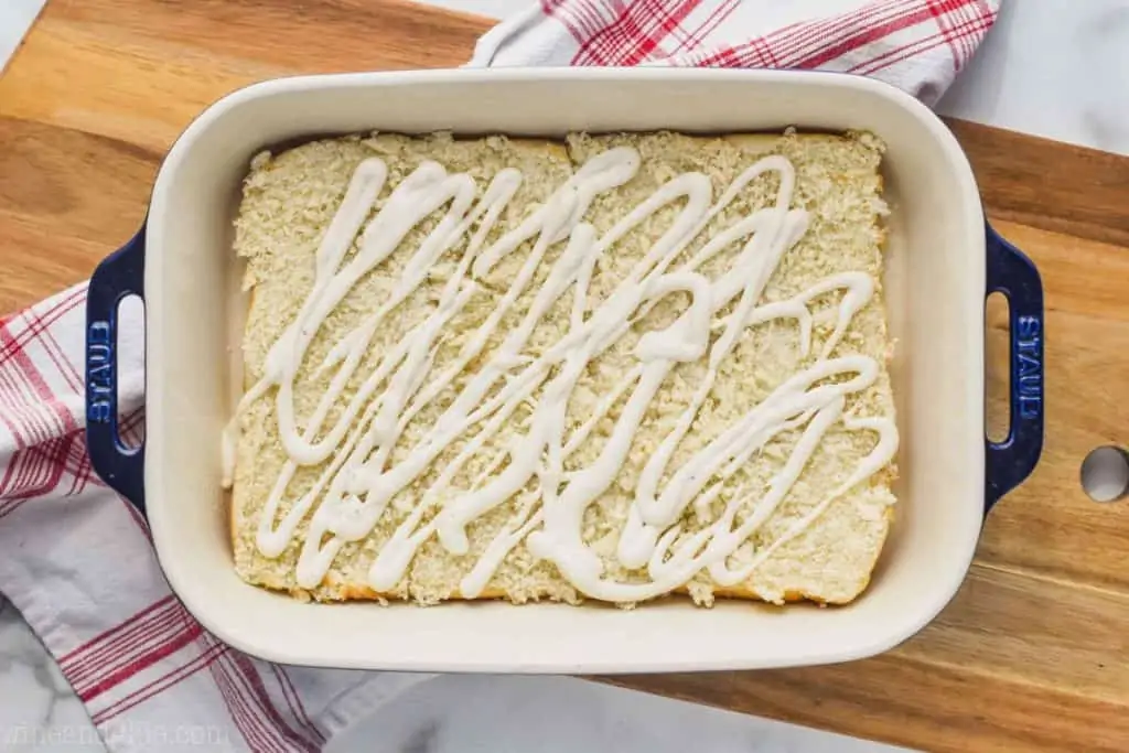landscape photo of a baking dish on a cutting board with the bottom half of slider rolls and ranch dressing on top - 2