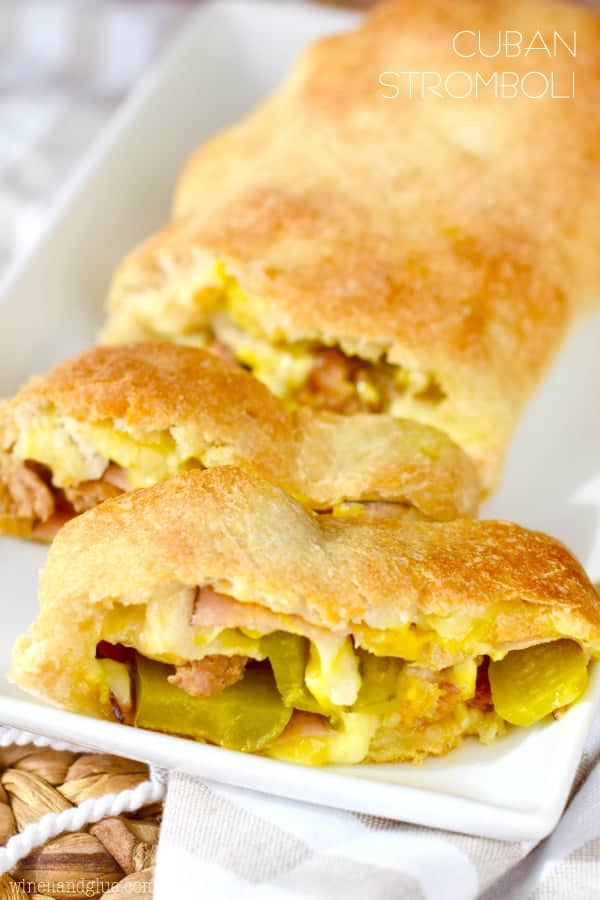 The Cuban Stromboli has a golden crust and in the middle, there is cheese oozing out, ham, sausage, and sliced pickles. 