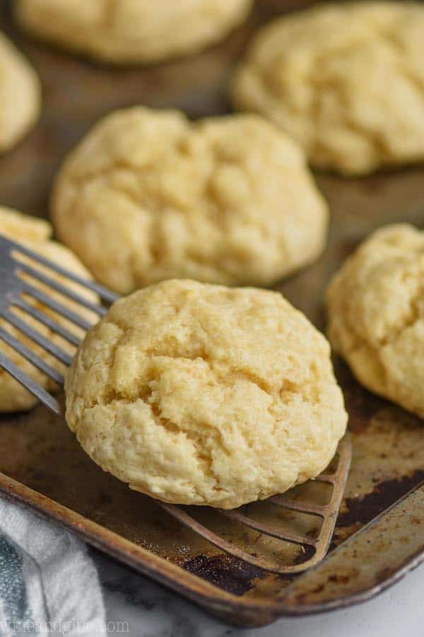 fast and easy drop biscuits being picked up by a metal spatula off a baking sheet
