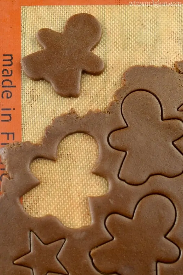 The Gingerbread Cookie Dough is rolled out flat and little shaped people are cut out of the dough. 