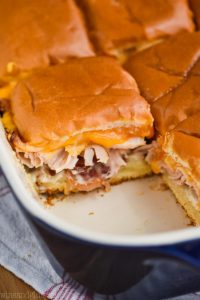 close up picture of a ceramic baking dish with bacon ranch turkey sliders in it, one missing