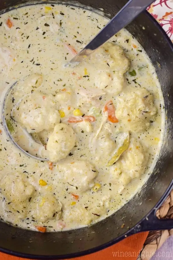 An overhead photo of the Turkey Dumpling Soup in a soup pot showing the creamy broth, balls of dumpling, chunks of turkey, slices of carrots, and corn. 