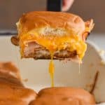 a turkey slider coming out of the pan with cheddar cheese stretching down