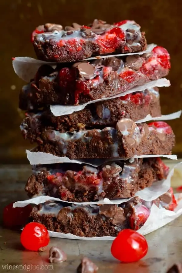 The Chocolate Covered Cherry Magic Bars is stacked high showing the speckles of red from the cherries, chocolate chips, and a white glaze from condensed milk.   