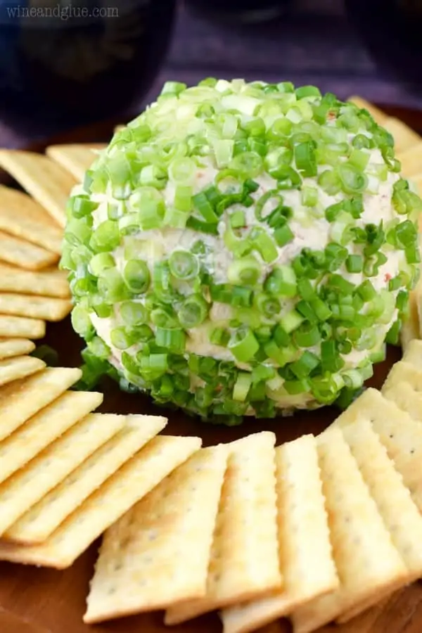 The Crab Dip Cheeseball has scallions covering the outside and surrounded by club crackers. 