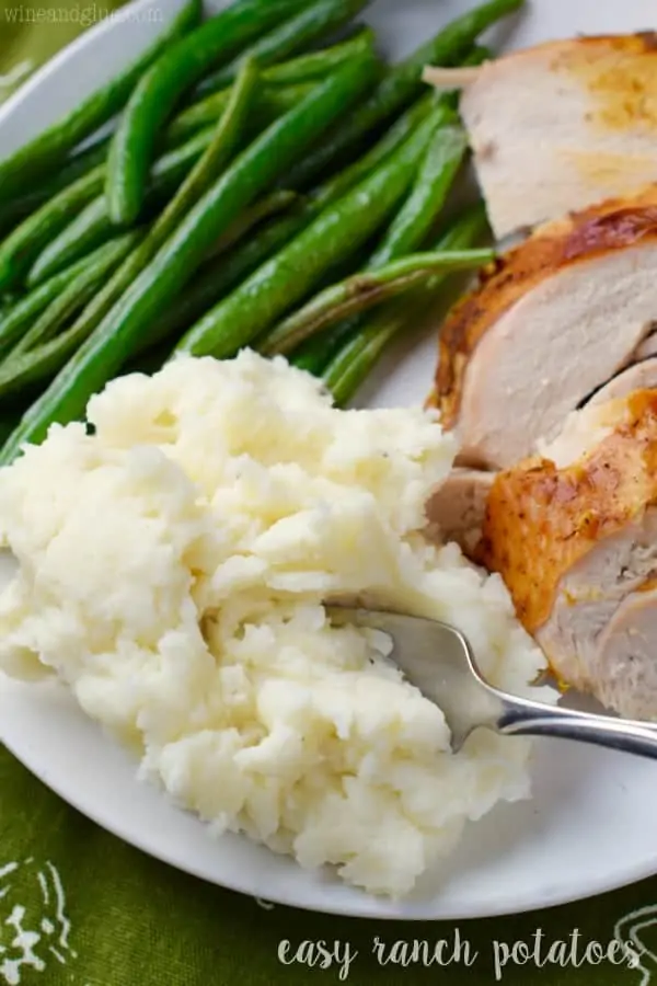 On a white plate, the Easy Ranch Potatoes is a side for roasted green beans and sliced chicken. 