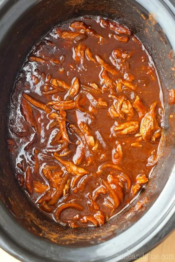 An overhead photo of crockpot with shredded chicken and BBQ sauce. 