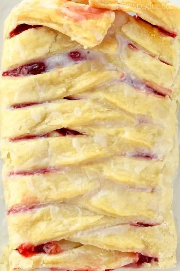 An overhead photo of the Cherry Almond Braid that has some cherry filling oozing out and glazed with some icing. 