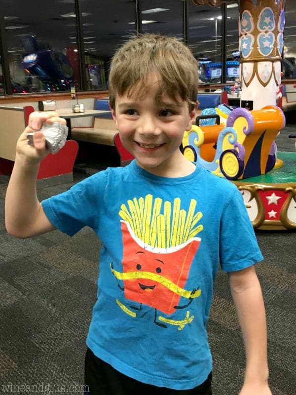 A little boy holding a stack of Chuck E. Cheese tickets. 