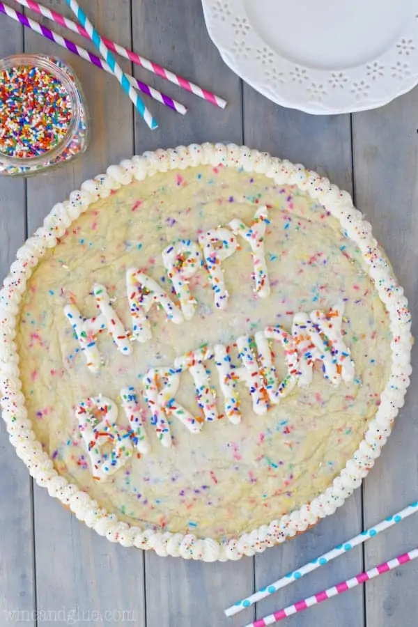 An overhead photo of the Funfetti Cookie Cake with white frosting on the side and the words of Happy Birthday in the middle topped with rainbow sprinkles. 