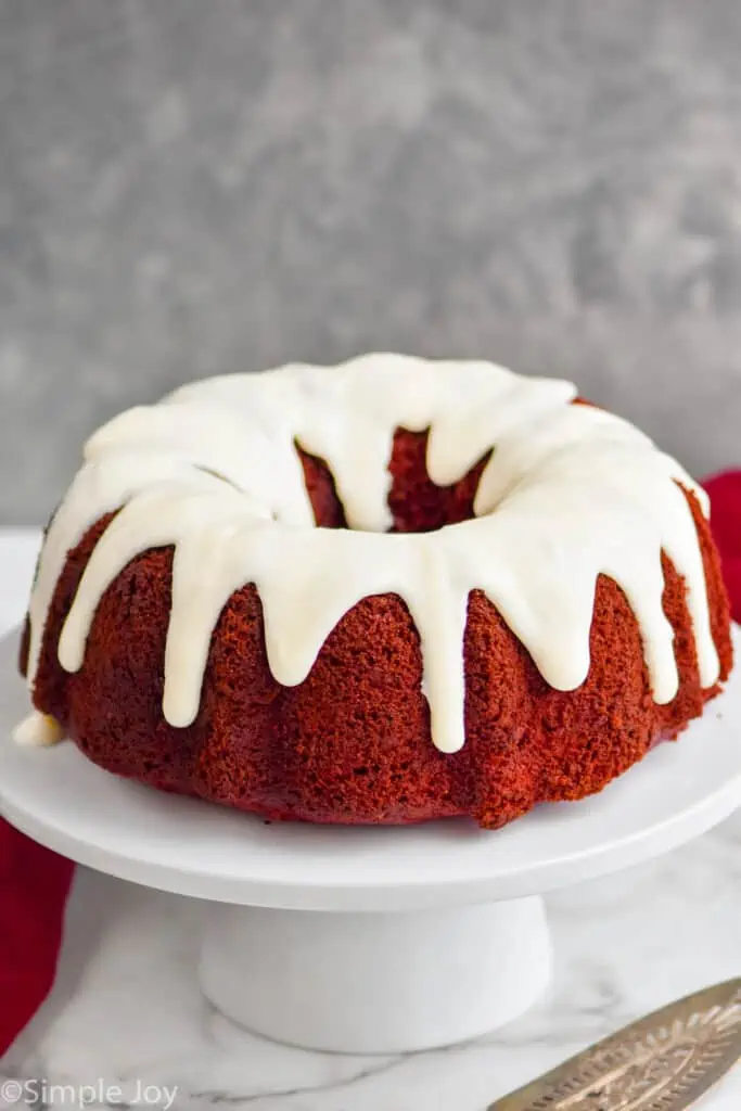 a red velvet cake frosted with cream cheese frosting on a cake stand