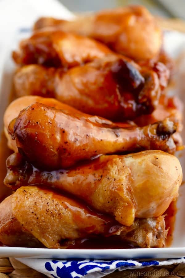 On a white plate, the Slow Cooker Honey BBQ Chicken Drumsticks has a crispy outside glazed with Honey BBQ. 