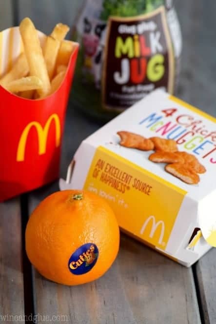 A photo of a children's meal from Mcdonalds with 4 Chicken McNuggets, Cuties, fries, and milk. 
