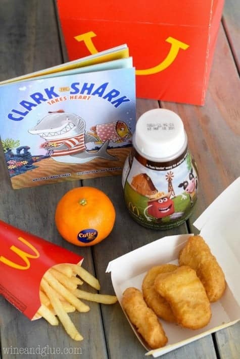 A photo of a children's meal from Mcdonalds with 4 Chicken McNuggets, Cuties, fries, and milk. 