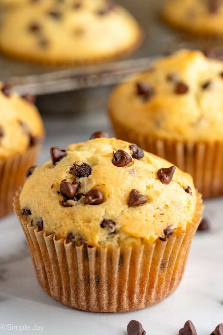 chocolate chip muffin with it's wrapper on, and more behind it