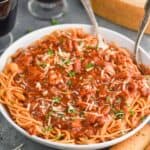a large white serving bowl full of chicken spaghetti - a spaghetti with red sauce and shredded chicken garnished with parsley and fresh parmesan - 15