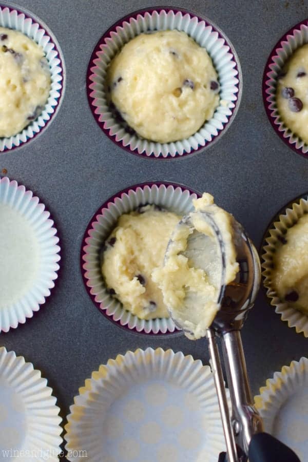 An overhead photo of a muffin tin with muffin liners and scoops of the One Bowl Chocolate Chip Muffins. 