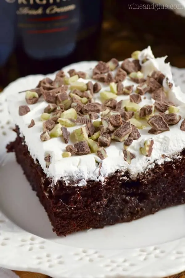 close up picture of a piece of bailey's poke cake on a plate topped with cool whip and broken up andes candies