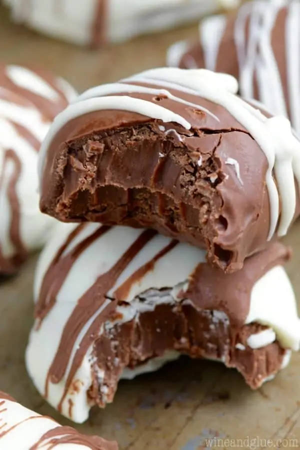 Two Fudge Filled Easter Eggs are stacked on top of each other with big bites (one dipped with white chocolate and the other dipped with milk chocolate). 