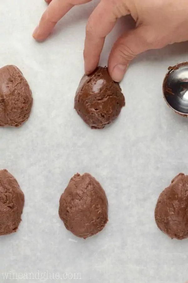 A woman is pinching the top of the fudge ball to create an egg shape. 