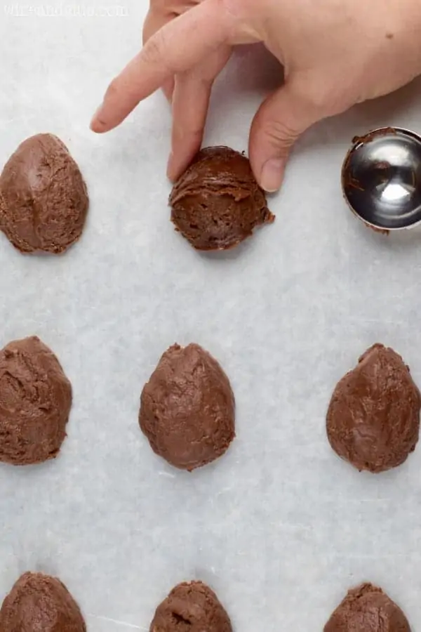 A woman pinches the top of the fudge ball to create an egg shape.