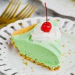 piece of green shamrock shake pie on a white plate topped with whipped cream and a cherry - 11